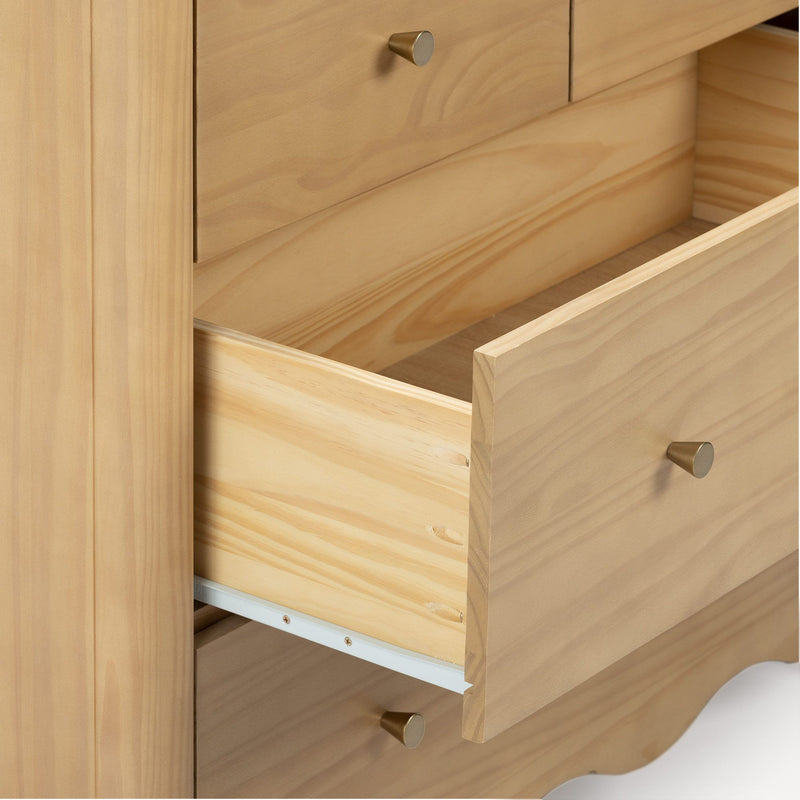 Close-up of open pine wood dresser drawers showing natural wood grain and brass cone knobs for bedroom storage