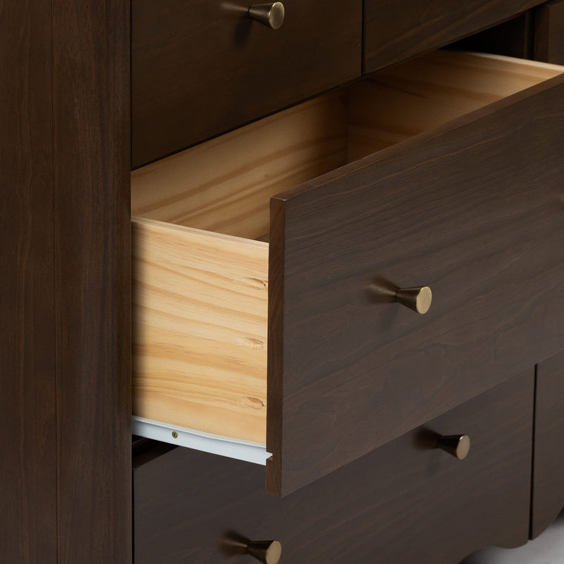 Close-up of dark-stained wood dresser with an open drawer showing light wood interior, brass knob pulls and smooth metal drawer slide
