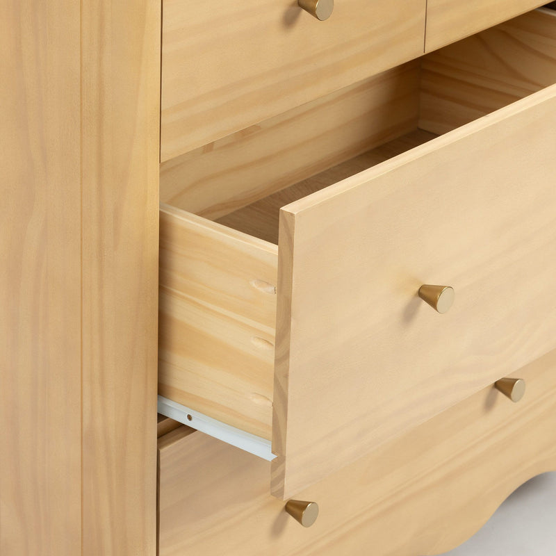 Close-up of a light wood dresser with an open drawer showing natural wood grain, visible drawer joinery and matte gold cone knobs, minimalist bedroom storage cabinet