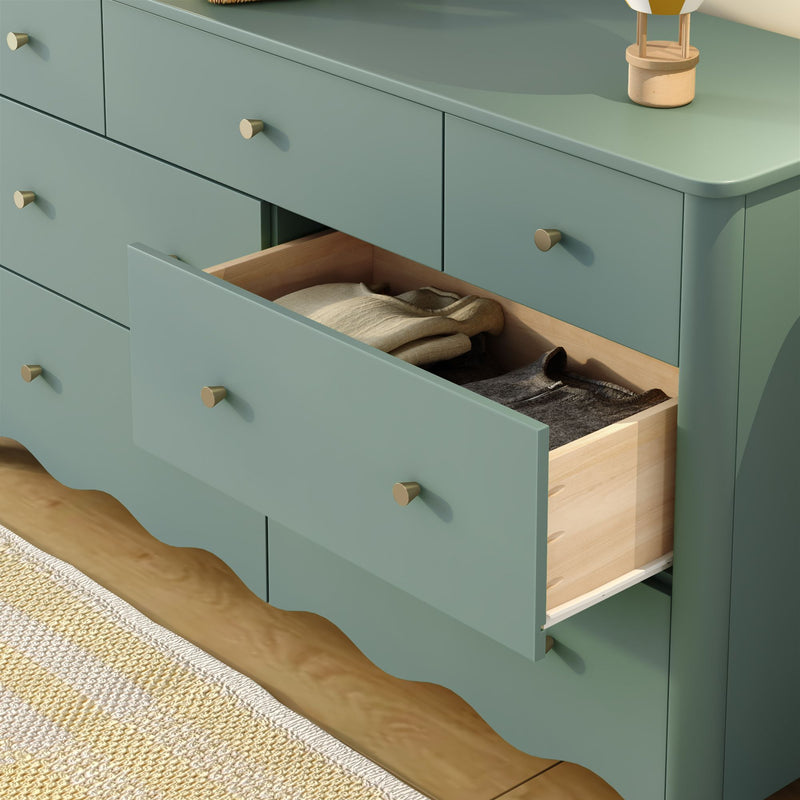 Child opening drawer of mint green dresser in colorful kids' bedroom with orange polka-dot wall, lamp and blue alarm clock