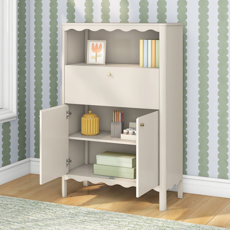 Beige wooden nursery storage cabinet with scalloped trim, open shelves holding pastel books, art frame and storage boxes against green scallop wallpaper