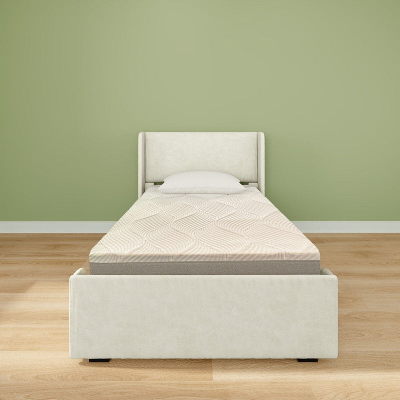 Single upholstered bed with memory-foam mattress and white pillow against a light green wall in a minimalist bedroom with hardwood floor