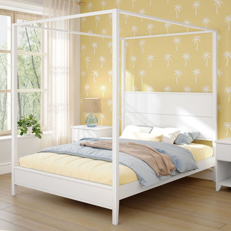 Sunlit bedroom with white canopy bed, yellow palm wallpaper, cozy blue-beige bedding, bedside lamp and plant