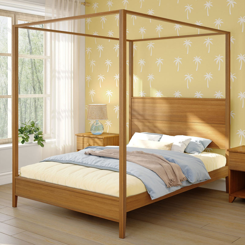 Cozy bedroom interior with wooden four-poster canopy bed, blue and beige bedding, yellow palm-print wallpaper, bedside lamp and sunlit window