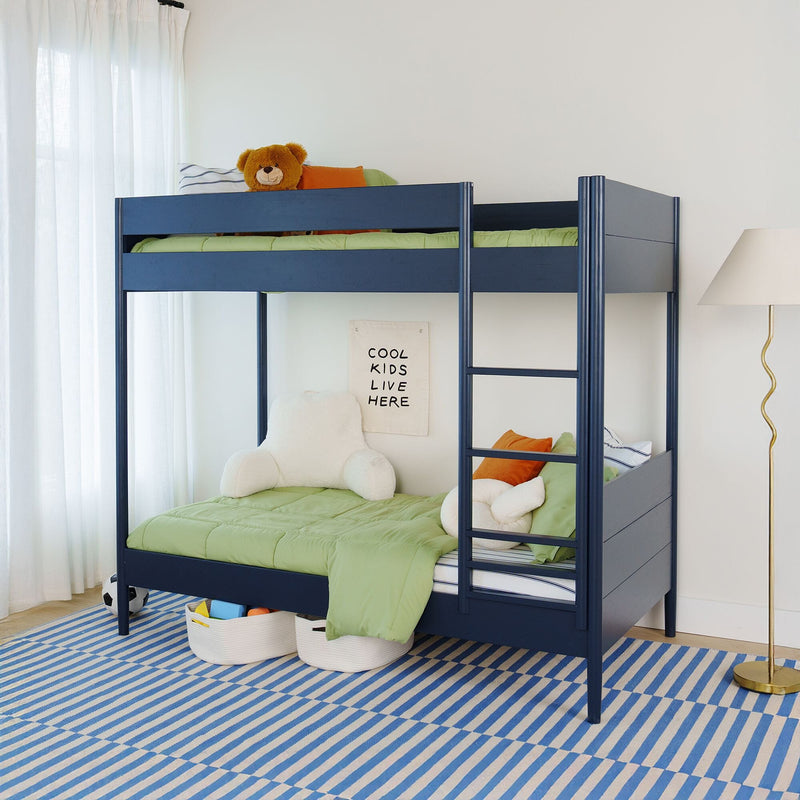 Navy blue kids bunk bed with green comforters, plush teddy bear, striped blue rug and modern lamp in bright bedroom