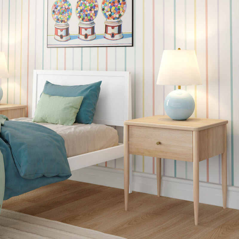 Cozy children's bedroom with white bed, teal and mint bedding, pastel striped wallpaper, light wood nightstand, blue ceramic lamp and gumball art