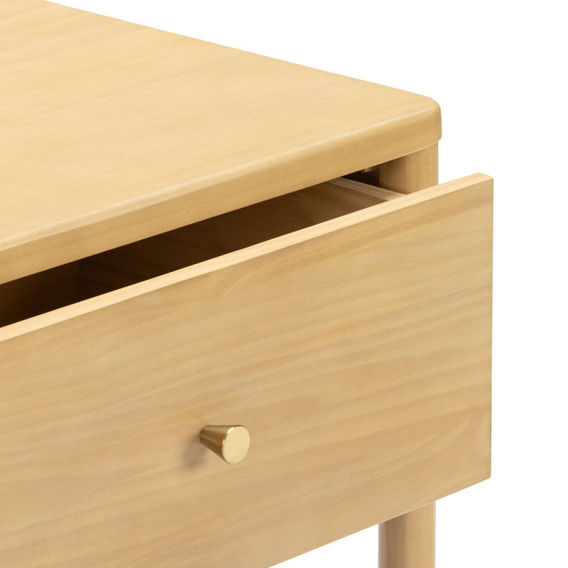 Light wood nightstand with partially open drawer, round brass knob and tapered legs in modern minimalist bedroom furniture style