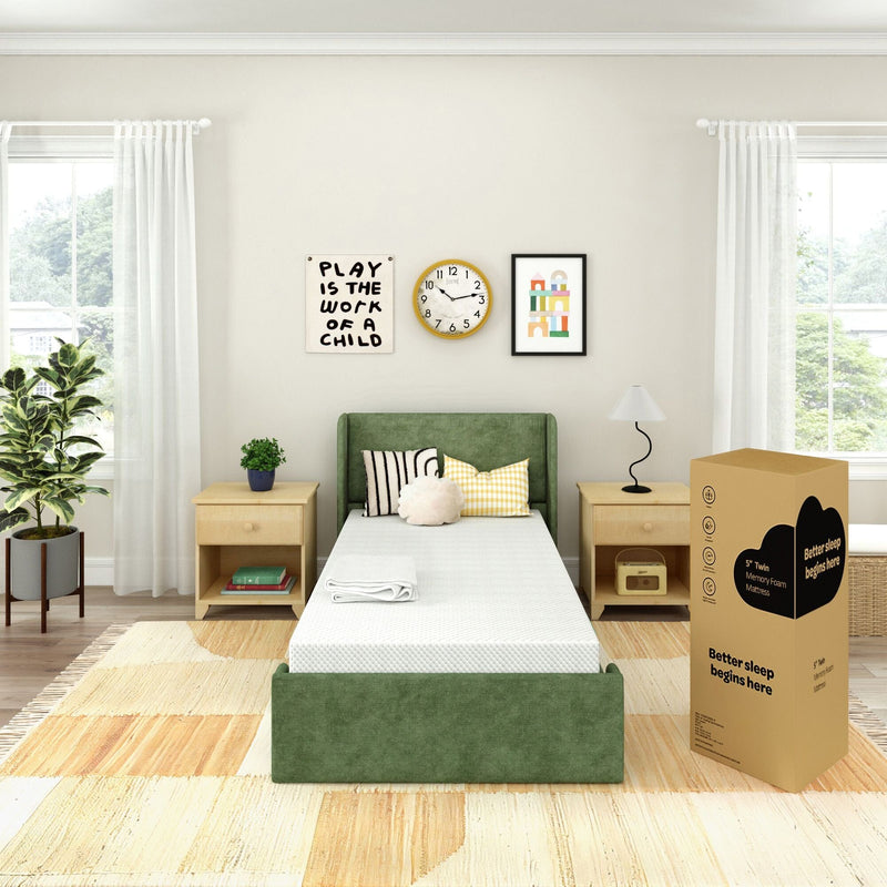 Bright children's bedroom with green upholstered twin bed and boxed memory foam mattress, wooden nightstands, plant, clock and "Play is the work of a child" wall art
