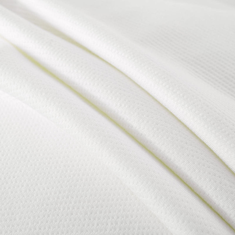 Close-up of folded white textured fabric with micro-waffle knit pattern, soft breathable material ideal for bedding, sheets, and apparel