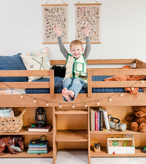 White low loft bed for kids with underbed play area and shelf storage in girls spring room