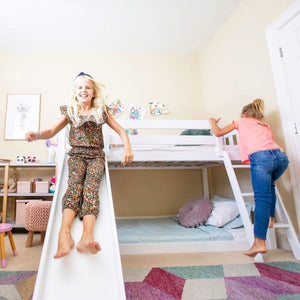 Low bunk bed with stairs and slide in white in shared girls room