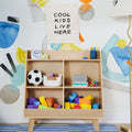 Kids playroom wooden cubby shelf with 'Cool Kids Live Here' wall banner, colorful foam blocks, soccer ball, clock and lamp
