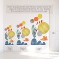 Abstract watercolor wall decals in yellow, orange, teal and blue on a white wall beside a door, showing scale comparison of small, medium and large kits for nursery, kids room and playroom decor