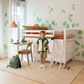 Kids bedroom with white bunk bed, green leaf wall decals, orange bedding, child in safari costume, study desk with microscope and globe, green backpack and toys