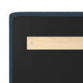Close-up of navy upholstered headboard back panel with black backing, light wood horizontal wall-mount bracket and metal screw
