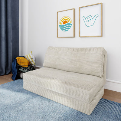 Modern coastal living room with beige textured sofa, blue rug, navy curtains, wire basket of decorative pillows and framed sun and shaka wall art