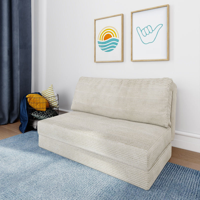 Minimalist living room with beige textured sofa, blue area rug, navy curtains, coastal sun and shaka framed wall art, and wire basket of yellow striped throw pillows.