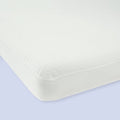 White hypoallergenic mattress protector on bed with light blue background.