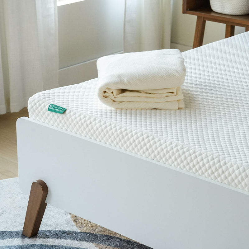 Optimal comfort memory foam mattress with folded linens on modern bed frame.