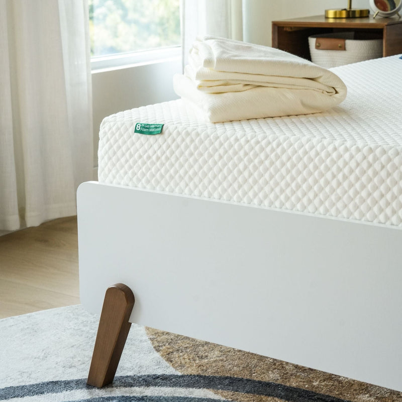 Premium 8-inch memory foam mattress on a modern bed frame with folded linens.
