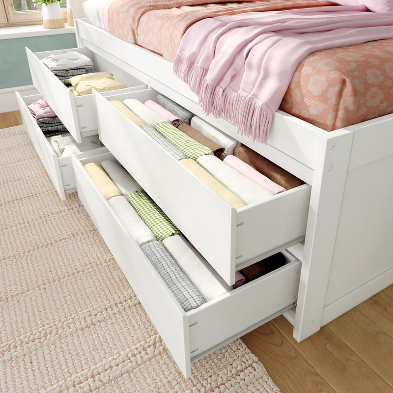 Under-bed storage drawers in white bed frame with neatly folded clothes, rolled linens, pink throw and floral bedding — space-saving bedroom organization