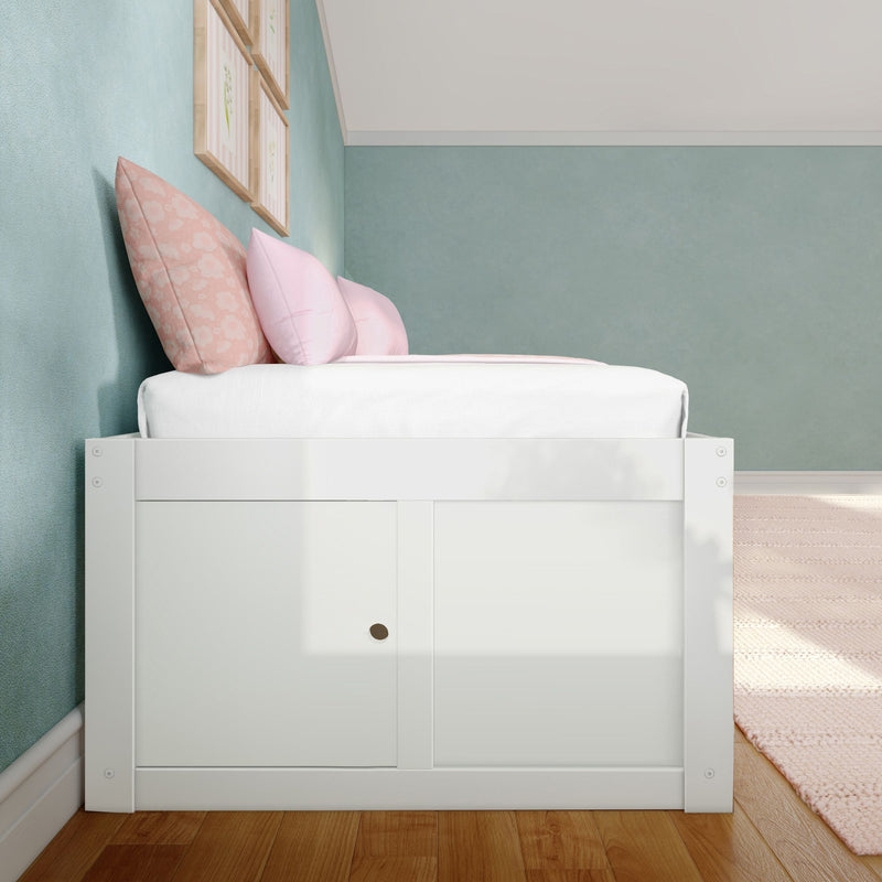 Pastel kids bedroom with white wooden storage bed, pink floral and blush pillows, teal textured accent wall, framed botanical prints and hardwood floor for modern nursery decor
