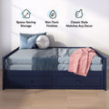 Modern navy blue storage daybed with under-bed drawers, light blue bedding, round white decorative pillow and pink throw in a small bedroom with wall icons highlighting space-saving storage, non-toxic finishes and classic style