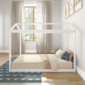 Neutral minimalist kids bedroom with white house-frame bed, beige curtains, wooden window, cozy bedding, striped pillows and plush toy