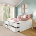 Storage bed with open under-bed drawers, pink floral bedding and pastel pillows in a mint-green bedroom with sheer curtains and botanical wall art