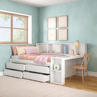 Cozy pastel kids bedroom with white platform storage bed and pull-out drawers, pink bedding and throw, mint-green textured walls, natural wood window, framed floral prints and white study desk