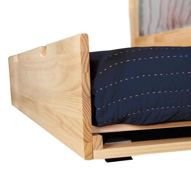 Close-up of natural pine platform bed frame with visible wood grain and navy quilted comforter, minimalist modern bedroom furniture detail