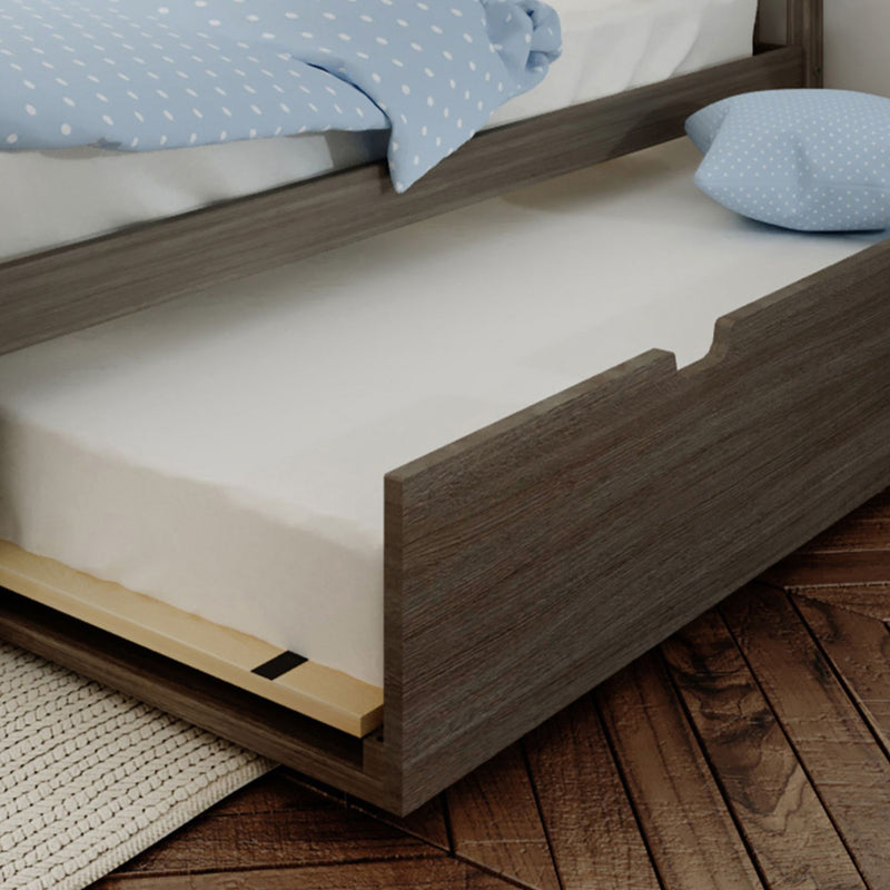 Under-bed trundle drawer pulled out from gray wood twin bed with white mattress and blue polka-dot bedding on hardwood floor