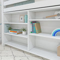 White built-in shelving under loft bed in kids' bedroom with colorful books, potted plants, cactus figurine, ukulele and rainbow toy