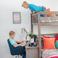 Child reading at desk beneath a wooden loft bed in a modern boys' bedroom – kids loft bed study nook with colorful pillows, toy car and Rubik's Cube