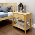 Close-up of children's bedroom with light wood bed and nightstand, house-shaped shelf holding numbered and icon toy blocks, gray pillows and blue bedding on hardwood floor