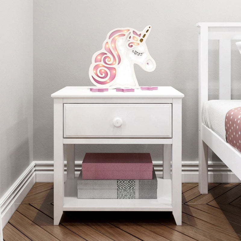 Pink unicorn LED night light on white wooden bedside table in a child's bedroom with pink polka-dot bedding and decorative storage boxes