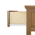 Open wooden dresser drawer with light plywood interior and white metal drawer slide, medium brown wood grain finish, side view on white background