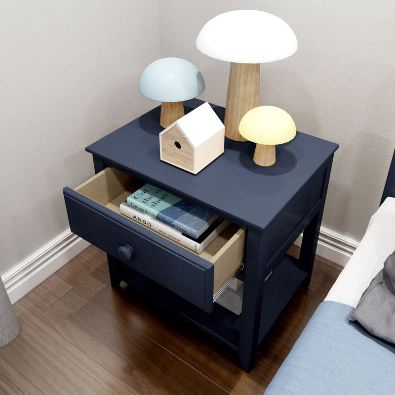 Navy blue bedside table with open drawer of books, three wooden mushroom lamps and small birdhouse on top in a modern bedroom with hardwood floor