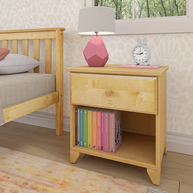 Wooden bedside table in children's bedroom with pink geometric lamp, bunny alarm clock, pastel children's books on lower shelf and natural light from window