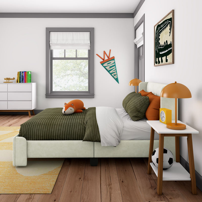 Kids bedroom interior with green striped bedding, fox plush toy, orange bedside lamps, personalized "Oliver" pennant, dinosaur wall art, white dresser with colorful books and toy airplane and soccer ball