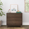 Dark wood mid-century three-drawer dresser in kids' nursery with framed animal car print, wooden toy boat, alphabet blocks and potted plant