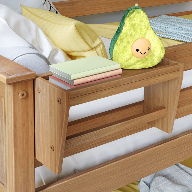 Avocado plush pillow on wooden bedside table with pastel books and yellow bedding, cozy bedroom decor