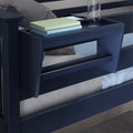 Navy blue bunk bed with built-in bedside shelf holding stacked pastel books and a clear water bottle in a modern bedroom