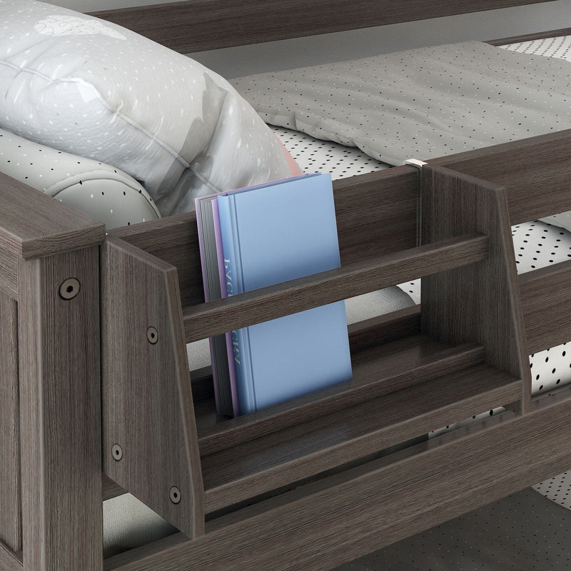 Wooden bunk bed with built-in bedside bookshelf holding blue and purple hardcover books, gray polka-dot sheets, and a white pillow