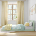 Pastel kids bedroom nursery with mint green bed, aqua-and-white bedding, yellow striped curtains, sun-shaped pillow, window plant and rainbow wall art