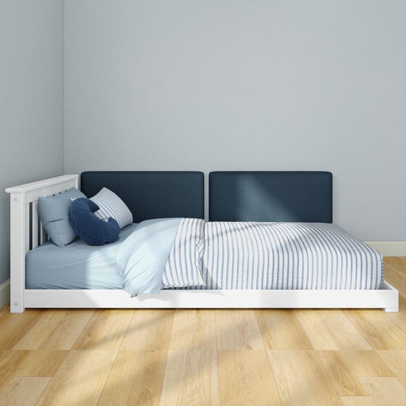 Minimalist blue bedroom: white single bed with navy upholstered headboard, light blue and striped bedding, hardwood floor and gray wall.
