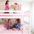 Four young girls playing a hand‑clap game on a white bunk bed with pink bedding and ladder in a bright, colorful children's bedroom