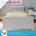 White solid pine bed frame with slatted headboard and footboard in a modern grey bedroom, yellow polka-dot duvet, bedside table with vase and pendant light, countersunk color-matched hardware
