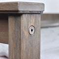Close-up of rustic wooden furniture leg with recessed hex bolt fastener and textured wood grain