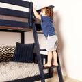 Toddler climbing navy bunk bed ladder in kids' bedroom, illustrating children's bunk bed safety and bedroom furniture